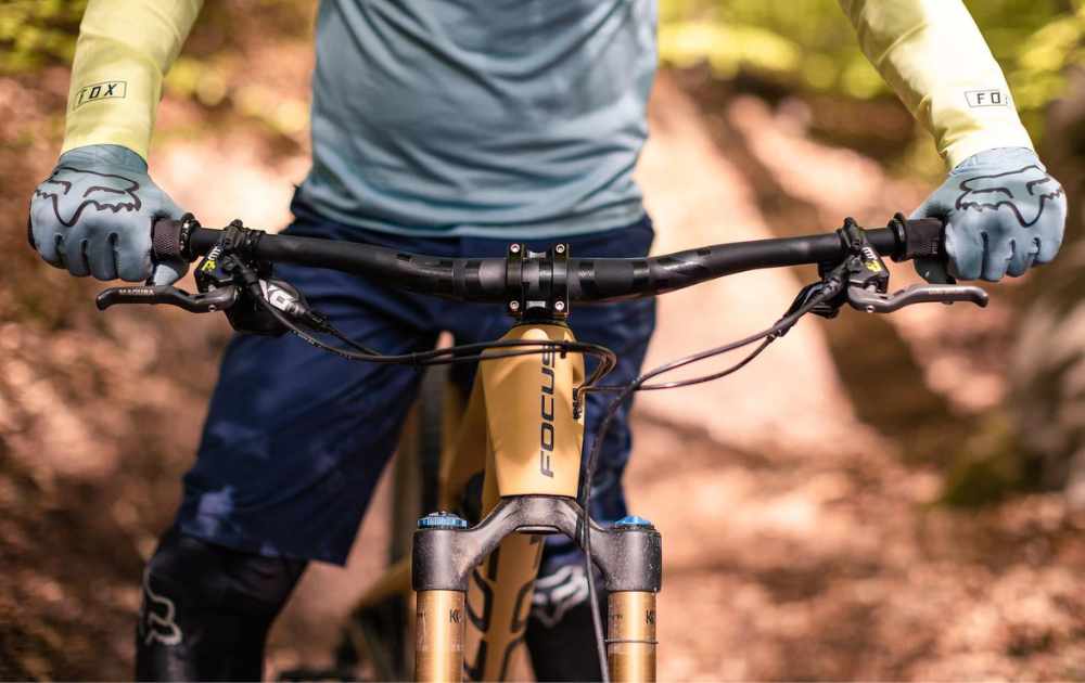 Cyklar i skogen med knäskydd och mountainbike